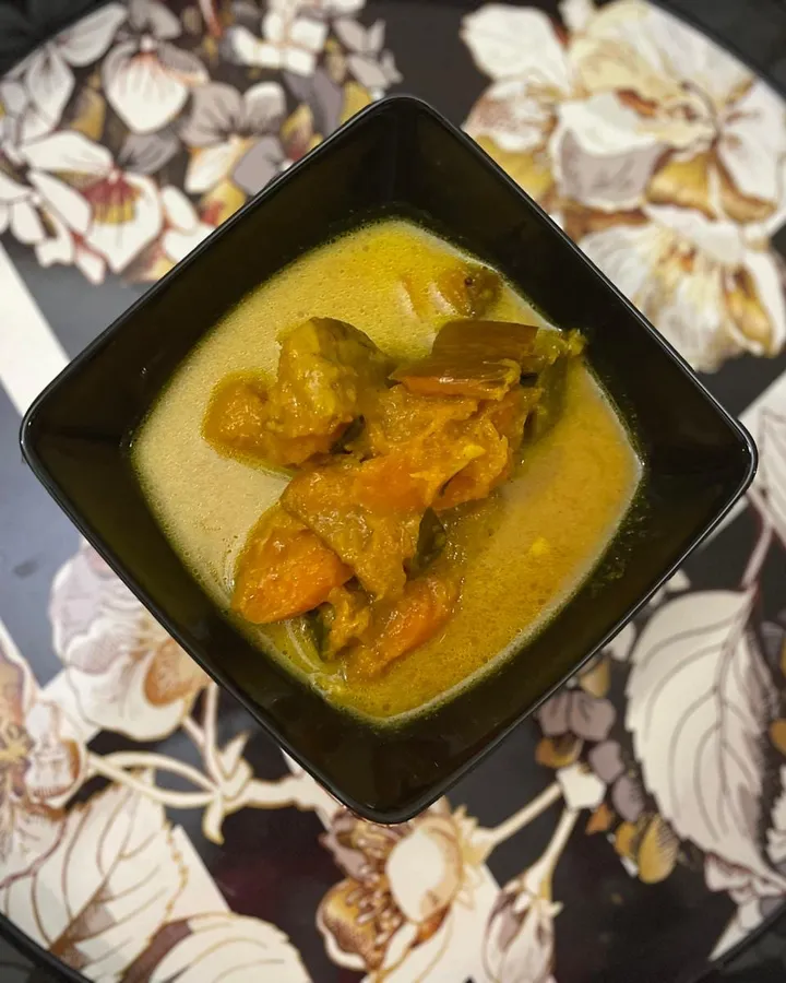 Sri Lankan pumpkin and carrot curry in a square black bowl on a floral serving tray