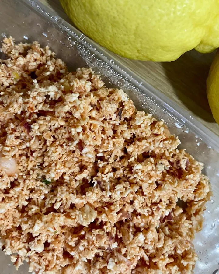 Coconut sambol in a clear container next to two whole lemons