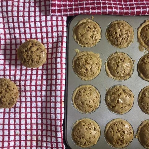 Golden-brown Sri Lankan cheesecake tarts in a 12-cup muffin tin, with two tarts on a red checked cloth